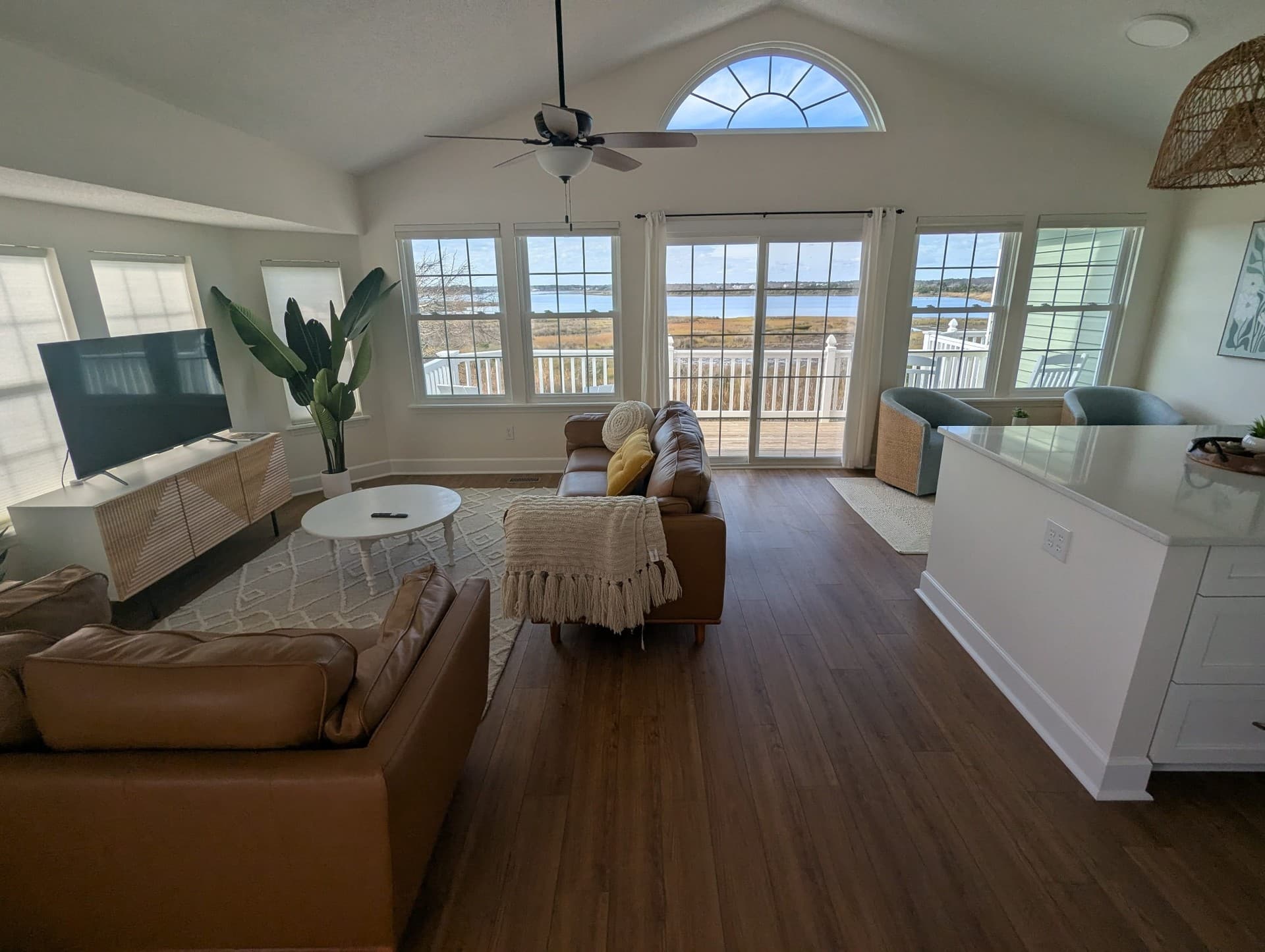 Open living room with leather seating, large windows, and sweeping marsh views beyond the deck.