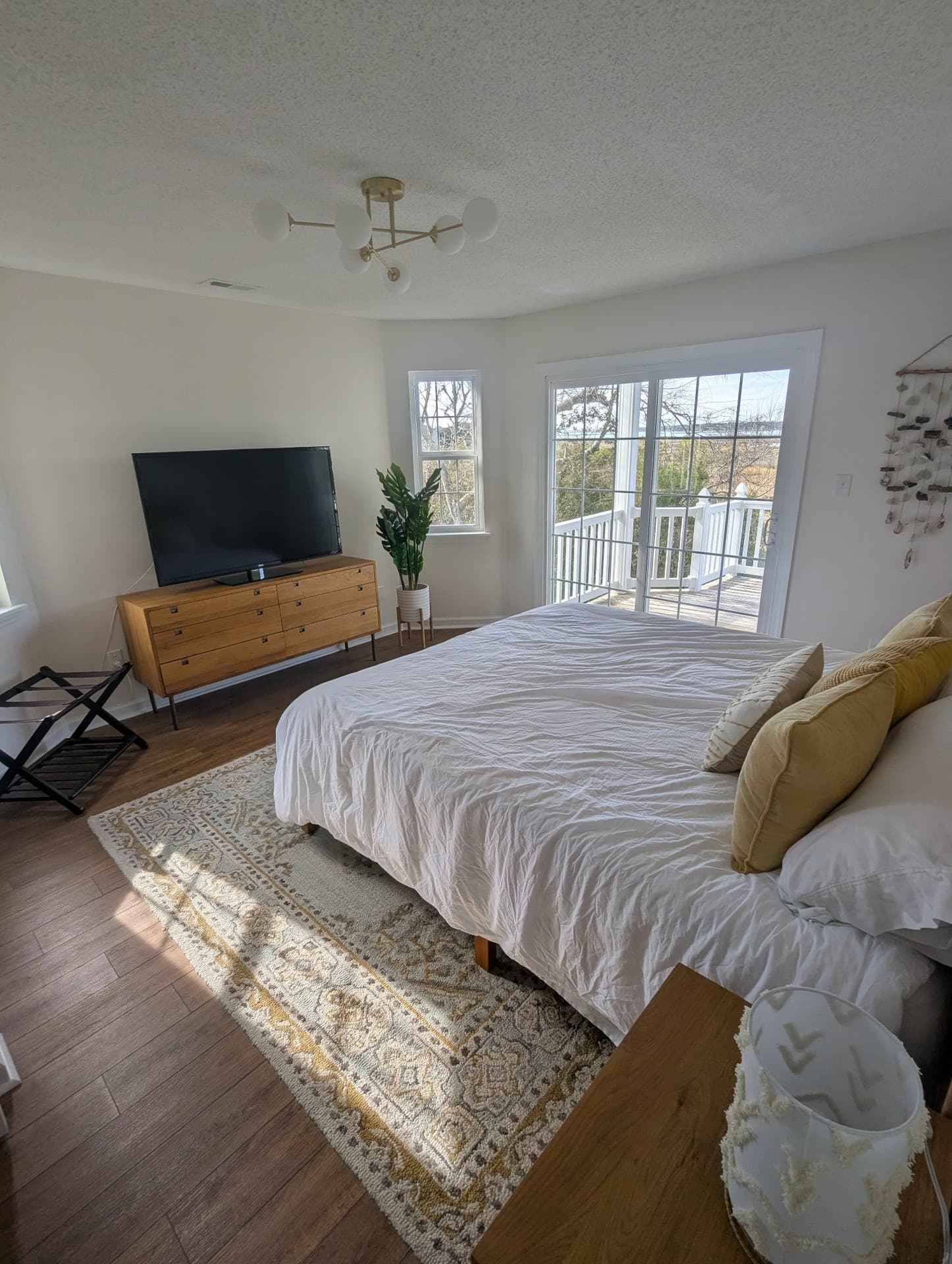 Bedroom with a large bed, sliding doors to a balcony, and marsh views beyond the windows.